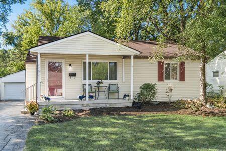 bungalow-style home with covered porch, a garage, an outbuilding, and a front yard