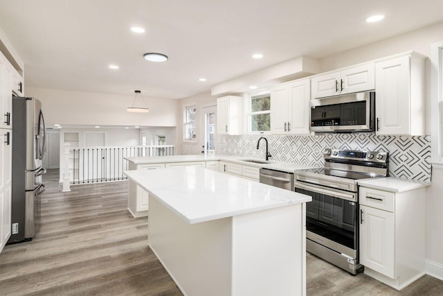 kitchen featuring pendant lighting, a kitchen island, stainless steel appliances, and light hardwood / wood-style floors