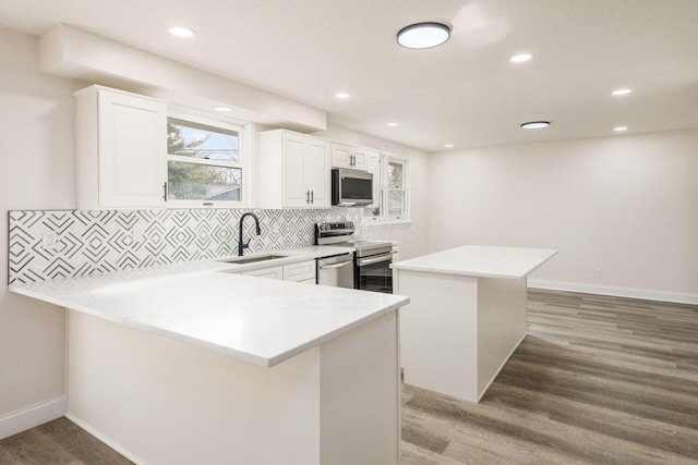 kitchen featuring sink, tasteful backsplash, hardwood / wood-style floors, white cabinets, and appliances with stainless steel finishes