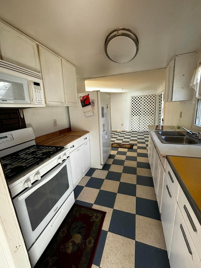 kitchen with white cabinets, white appliances, and sink