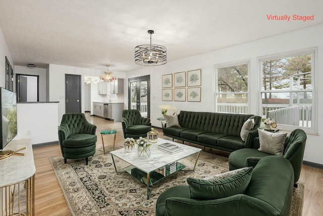 living room with plenty of natural light, light hardwood / wood-style floors, and an inviting chandelier