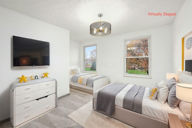 carpeted bedroom featuring a textured ceiling and an inviting chandelier