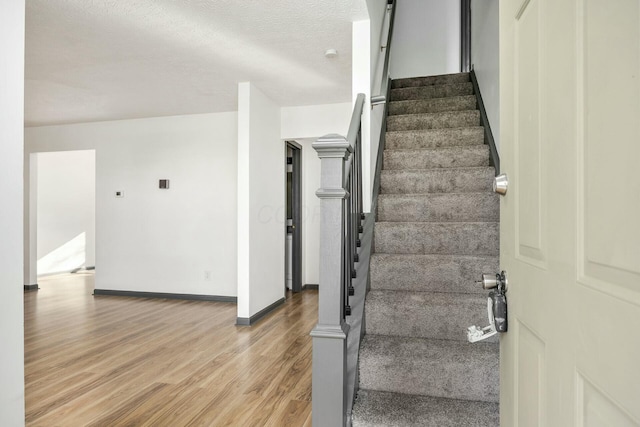 stairs featuring wood-type flooring and a textured ceiling