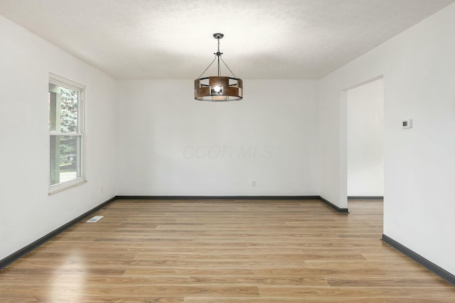 empty room featuring a textured ceiling and light wood-type flooring