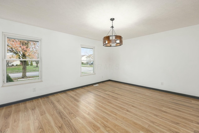 unfurnished room featuring light hardwood / wood-style floors and a textured ceiling