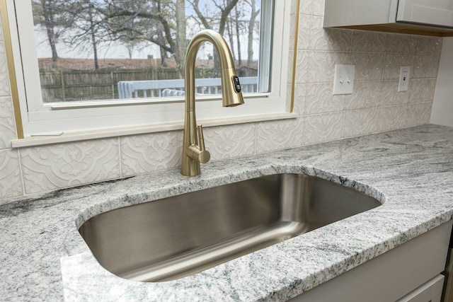 interior details featuring light stone countertops and sink