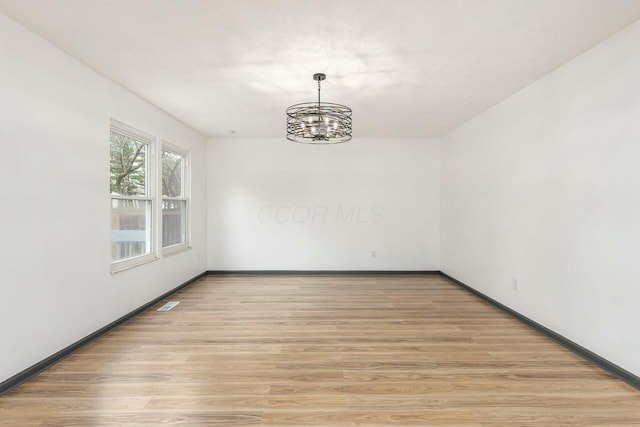 spare room with a chandelier and light hardwood / wood-style flooring