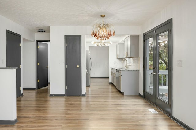 kitchen with sink, stainless steel appliances, an inviting chandelier, a textured ceiling, and gray cabinets