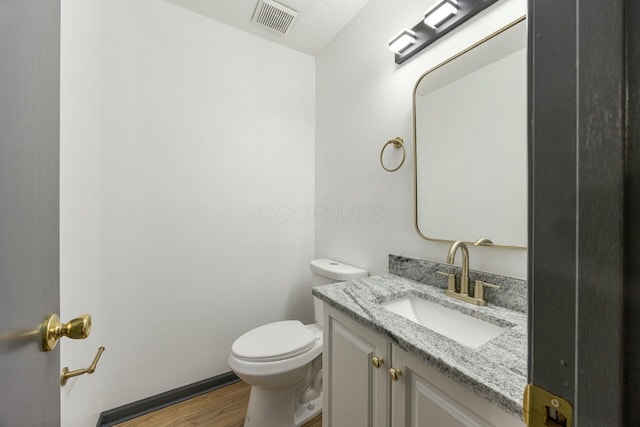 bathroom with hardwood / wood-style floors, vanity, and toilet