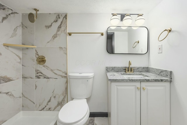 bathroom featuring a tile shower, vanity, a textured ceiling, and toilet