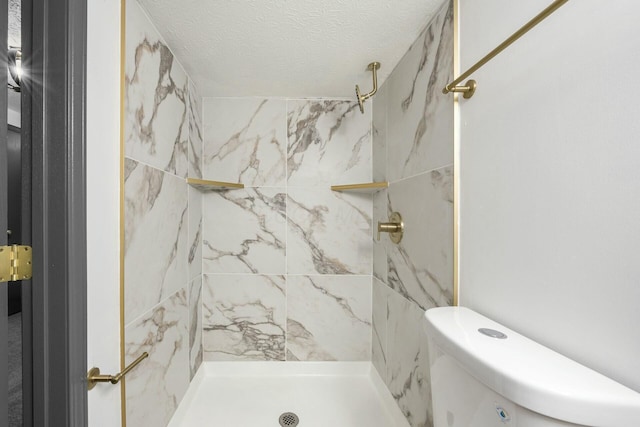 bathroom with a tile shower, a textured ceiling, and toilet