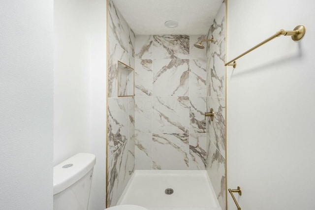 bathroom featuring toilet and tiled shower