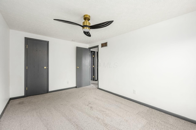 carpeted spare room featuring a textured ceiling and ceiling fan