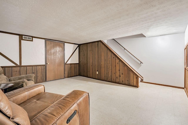 interior space with a textured ceiling and wood walls