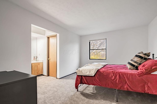 bedroom featuring a textured ceiling, light colored carpet, sink, and connected bathroom