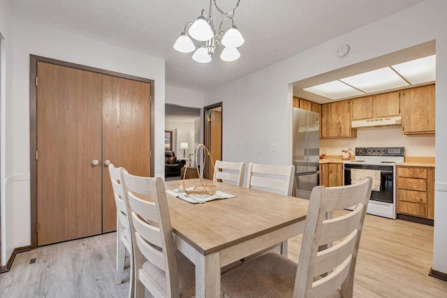 dining area with a notable chandelier, light hardwood / wood-style floors, and a textured ceiling