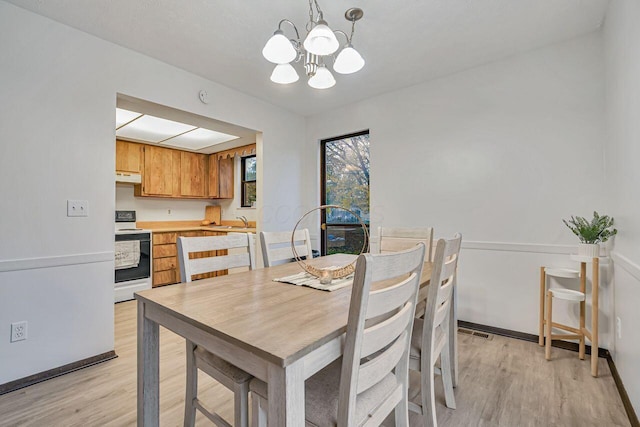 dining space featuring a chandelier, light hardwood / wood-style floors, and sink