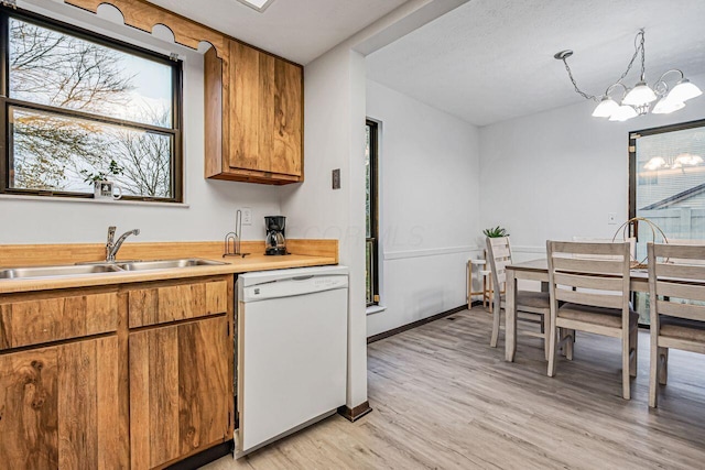 kitchen with white dishwasher, sink, light hardwood / wood-style flooring, a chandelier, and hanging light fixtures