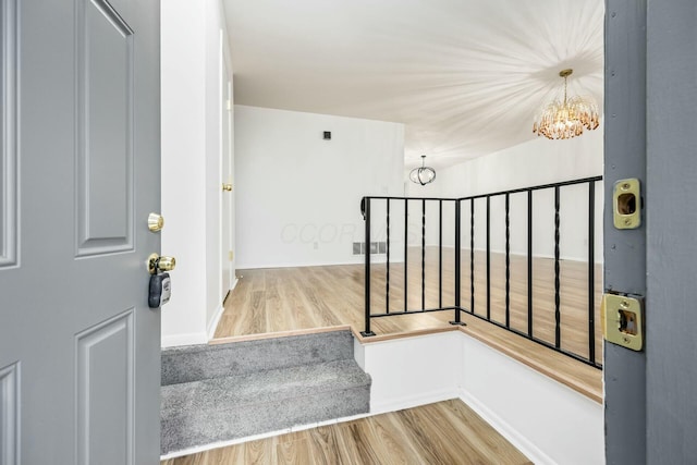 stairs with a notable chandelier and wood-type flooring