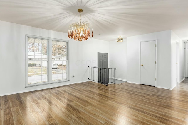 spare room with hardwood / wood-style flooring and an inviting chandelier