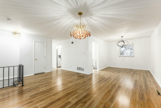 empty room featuring a chandelier and wood-type flooring