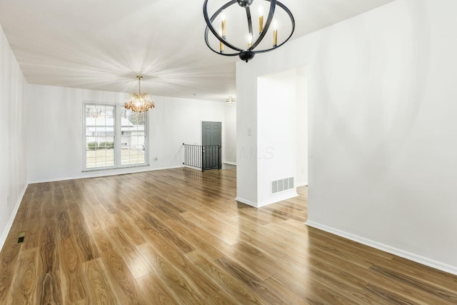 unfurnished living room featuring wood-type flooring and an inviting chandelier