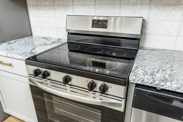 kitchen featuring white cabinets, light stone countertops, and stainless steel range