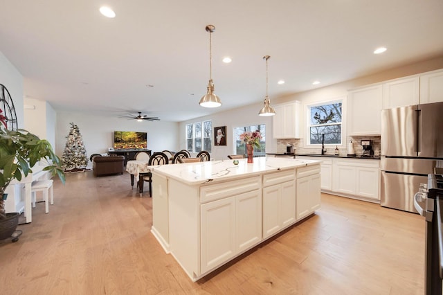 kitchen featuring light hardwood / wood-style flooring, a kitchen island, hanging light fixtures, and appliances with stainless steel finishes