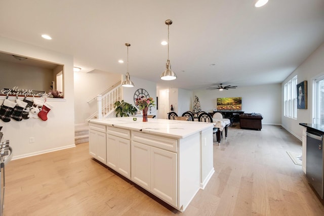 kitchen featuring decorative light fixtures, a center island, light stone counters, and light wood-type flooring