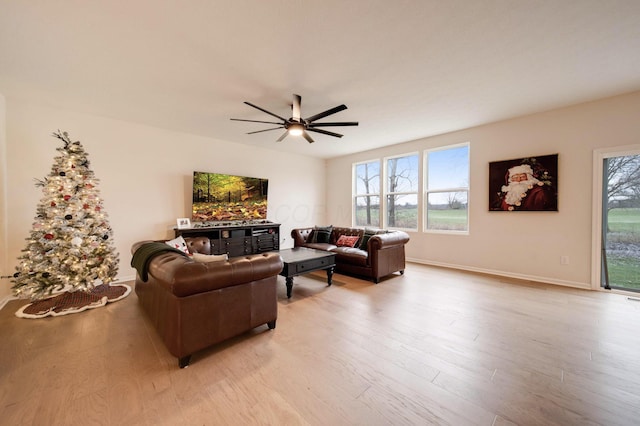 living room with light hardwood / wood-style flooring, ceiling fan, and a healthy amount of sunlight