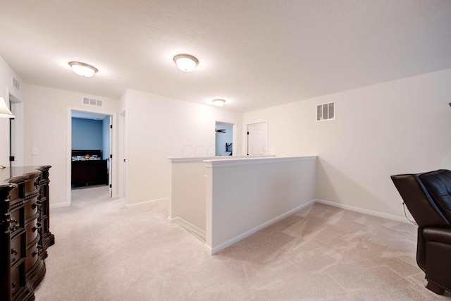 hall featuring light carpet and a textured ceiling