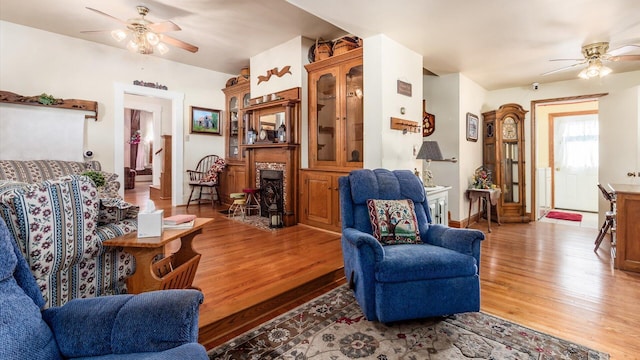 living room with a stone fireplace, ceiling fan, and hardwood / wood-style flooring