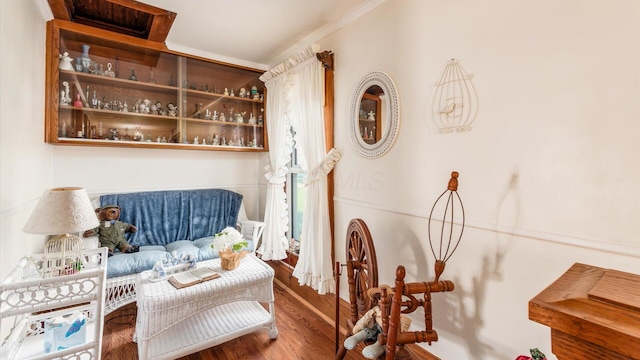 sitting room with crown molding and wood-type flooring