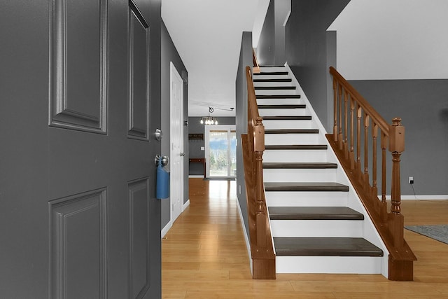 stairway featuring hardwood / wood-style flooring and an inviting chandelier