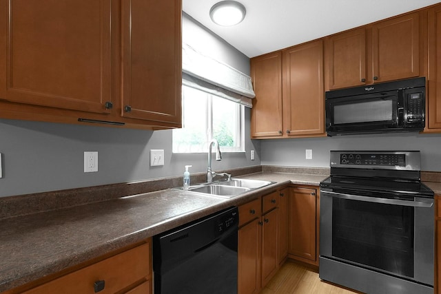 kitchen featuring sink, black appliances, and light hardwood / wood-style flooring