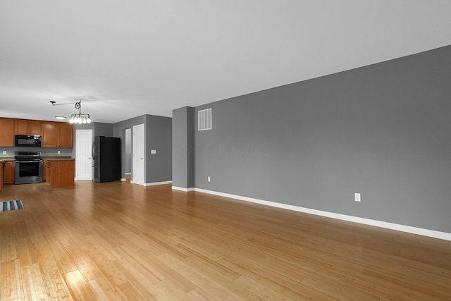 unfurnished living room featuring light wood-type flooring and a notable chandelier