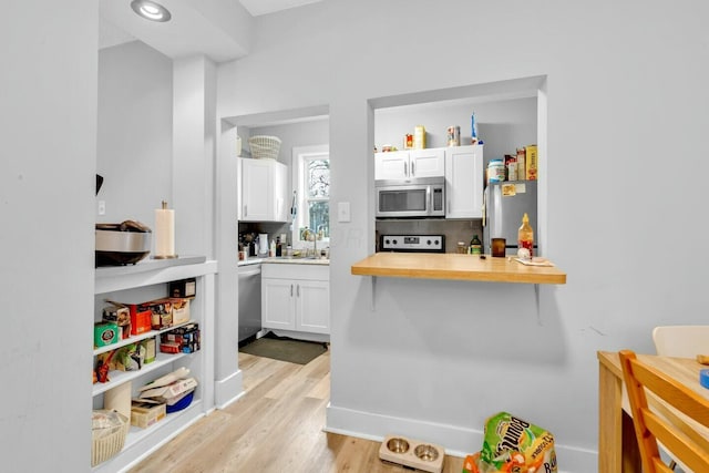 kitchen featuring sink, butcher block countertops, light hardwood / wood-style floors, white cabinetry, and stainless steel appliances