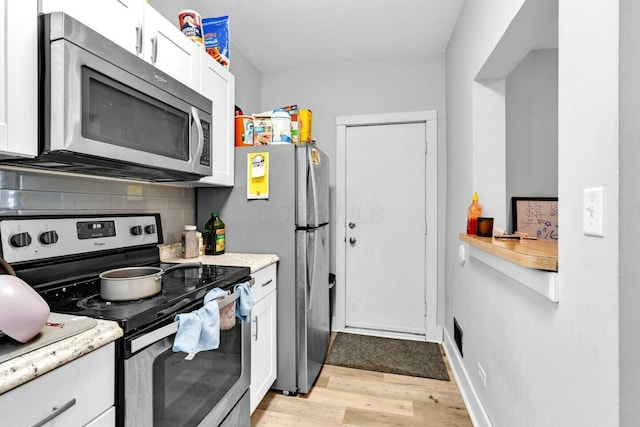 kitchen featuring backsplash, white cabinetry, light hardwood / wood-style flooring, and stainless steel appliances