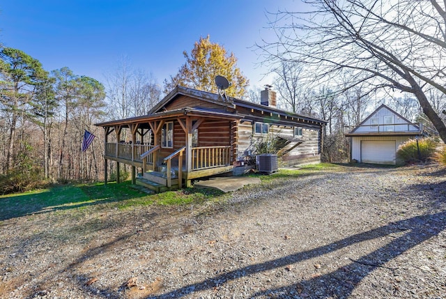 view of front of property featuring a porch, a garage, an outdoor structure, and central air condition unit