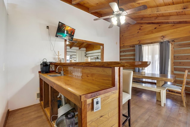 dining room with sink, wooden ceiling, lofted ceiling with beams, wood walls, and light wood-type flooring