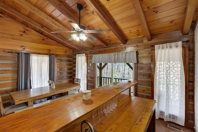 unfurnished dining area with hardwood / wood-style floors, lofted ceiling with beams, a wealth of natural light, and wooden walls