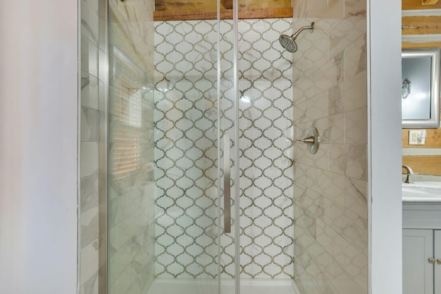 bathroom with a tile shower and vanity