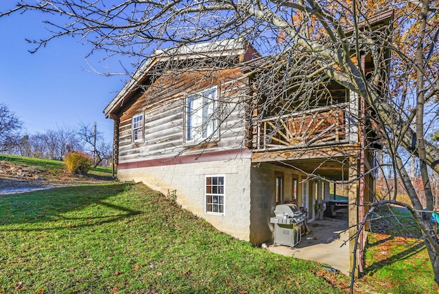 view of side of property featuring a patio area and a lawn