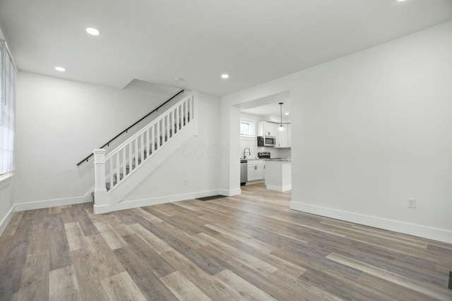 unfurnished living room with light hardwood / wood-style flooring and sink