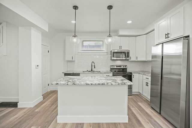 kitchen with a center island, stainless steel appliances, light hardwood / wood-style flooring, decorative light fixtures, and white cabinets