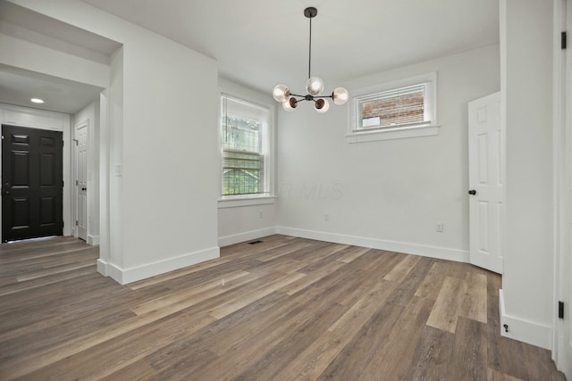 unfurnished dining area featuring dark hardwood / wood-style floors and an inviting chandelier