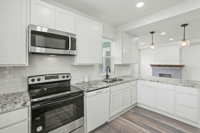 kitchen featuring sink, light hardwood / wood-style flooring, decorative light fixtures, white cabinets, and appliances with stainless steel finishes