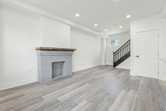 unfurnished living room with light hardwood / wood-style floors and a brick fireplace