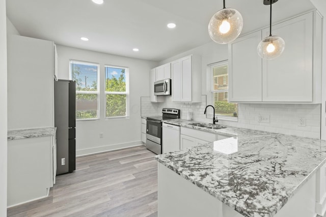 kitchen featuring stainless steel appliances, plenty of natural light, hanging light fixtures, and sink