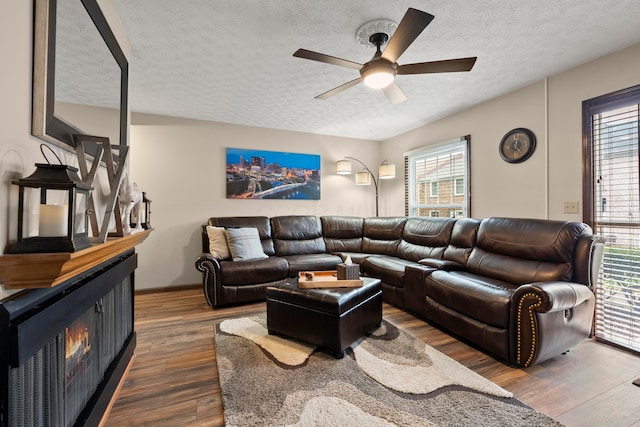 living room with a textured ceiling, plenty of natural light, dark wood-type flooring, and ceiling fan